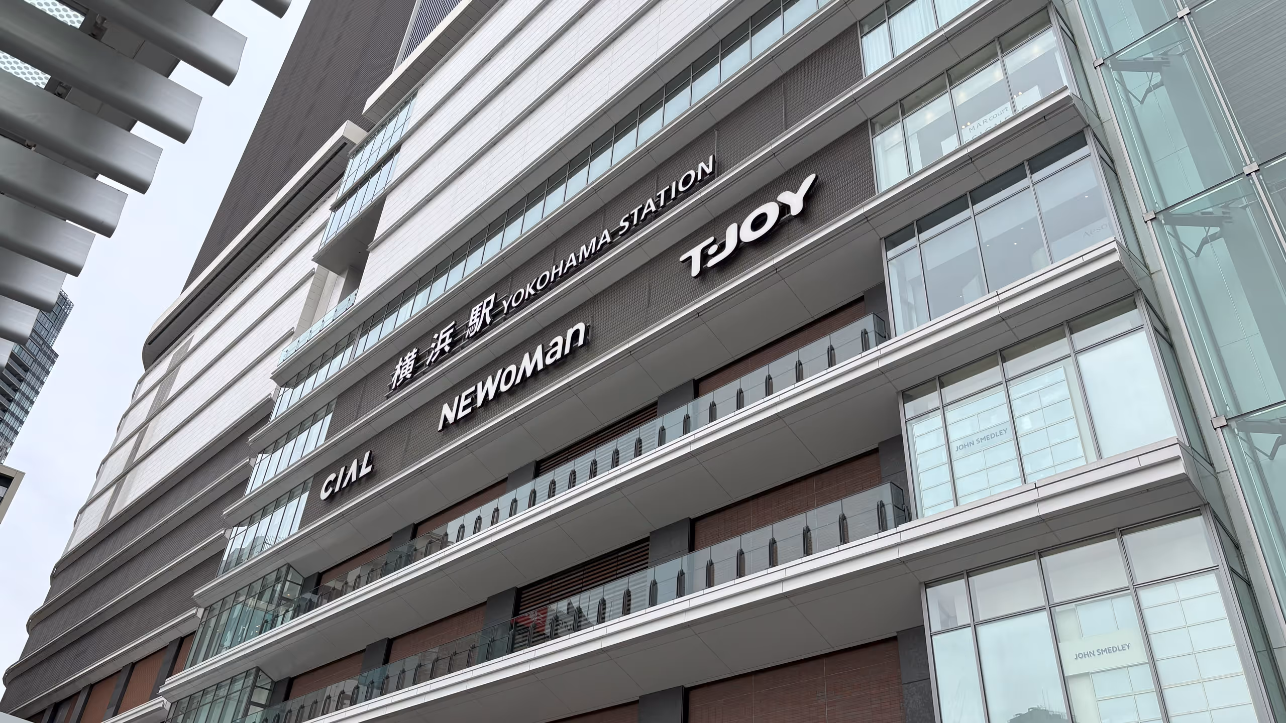 ガラス張りの何の変哲もないビルの壁に、横浜駅の案内とCIALと、NEWoMan、T・joyのロゴが並ぶ。