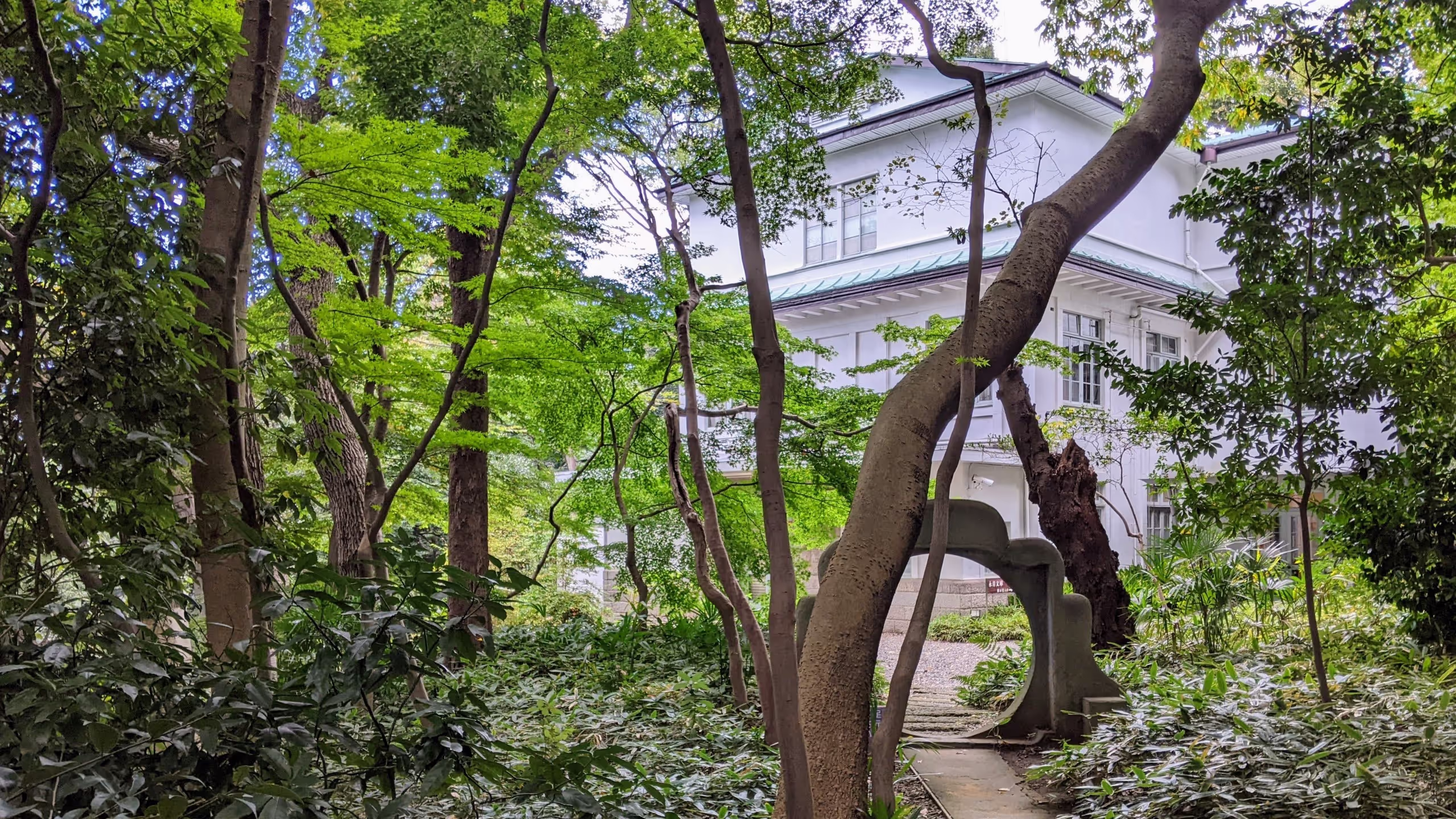 木々に囲まれた石のくぐり門の先に、白壁に緑の屋根が葺かれた和風な洋館がひっそりと建っている