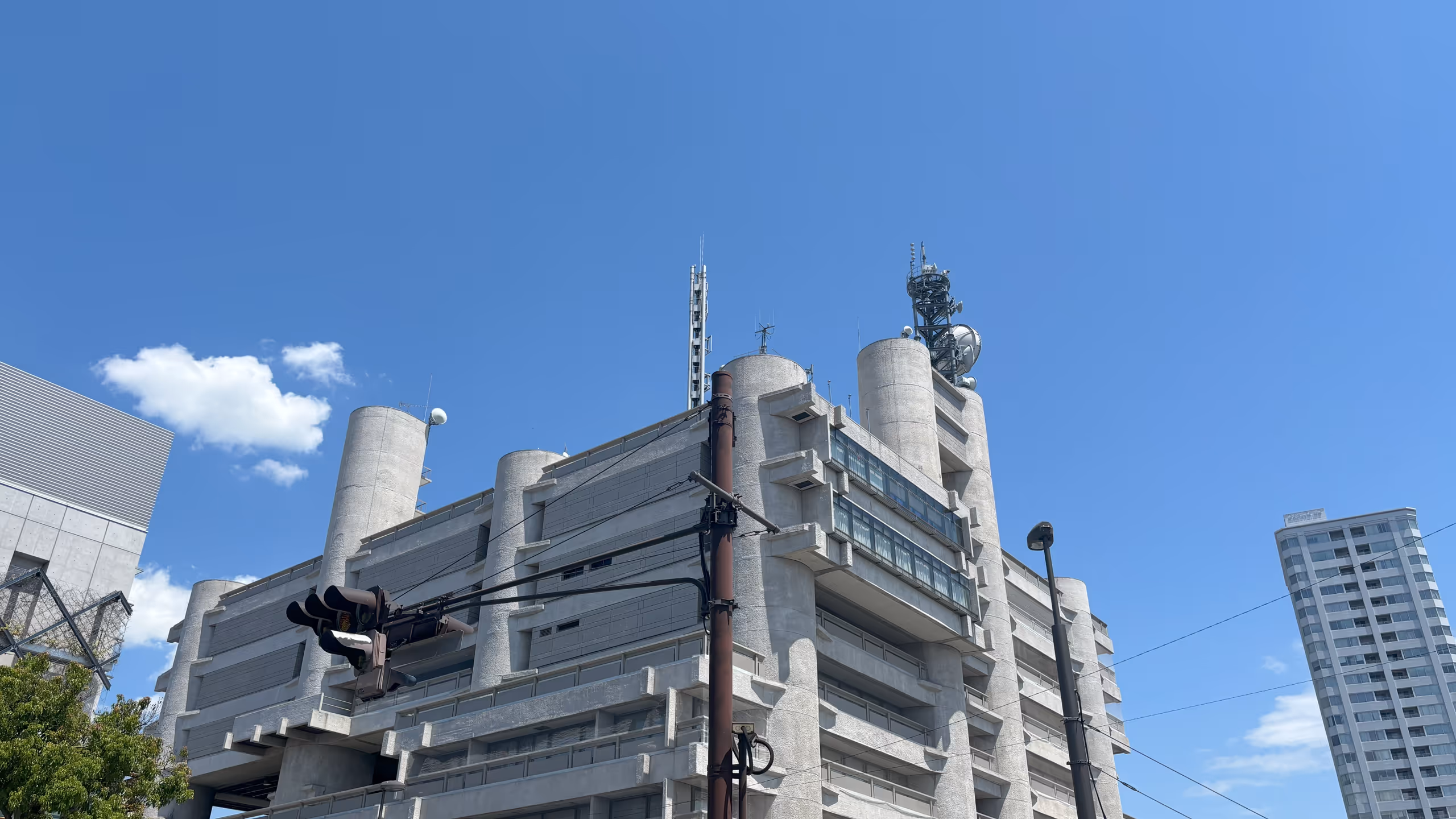 茶色い信号機の向こうに灰色の大きな建物が聳えている。いくつかの巨大な円柱の間を平らな壁面が繋ぐ、迫力のあるコンクリート造りだ。あまり窓は見えない。