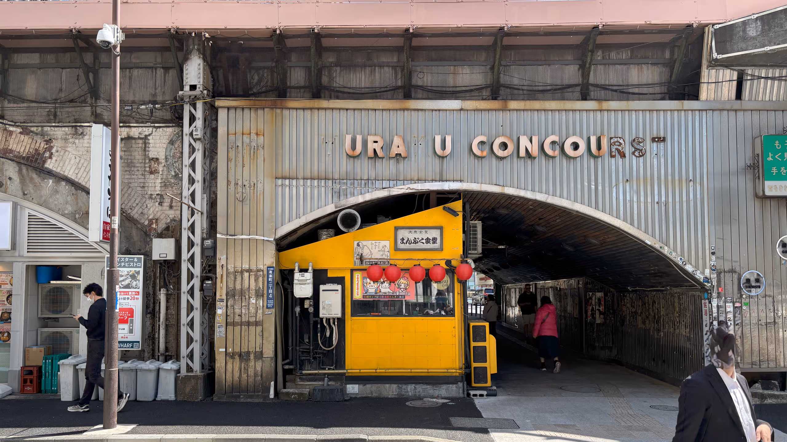 高架下に、飲食店のあるコンコースが設けられている。出口の飲食店はオレンジの壁に赤ちょうちんがぶら下がっている。高架を支える屋根部分には「YURAKU CONCOURS」という名称のロゴが掲げられているものの、YやK、最後のRSが欠けてしまっているようだ。