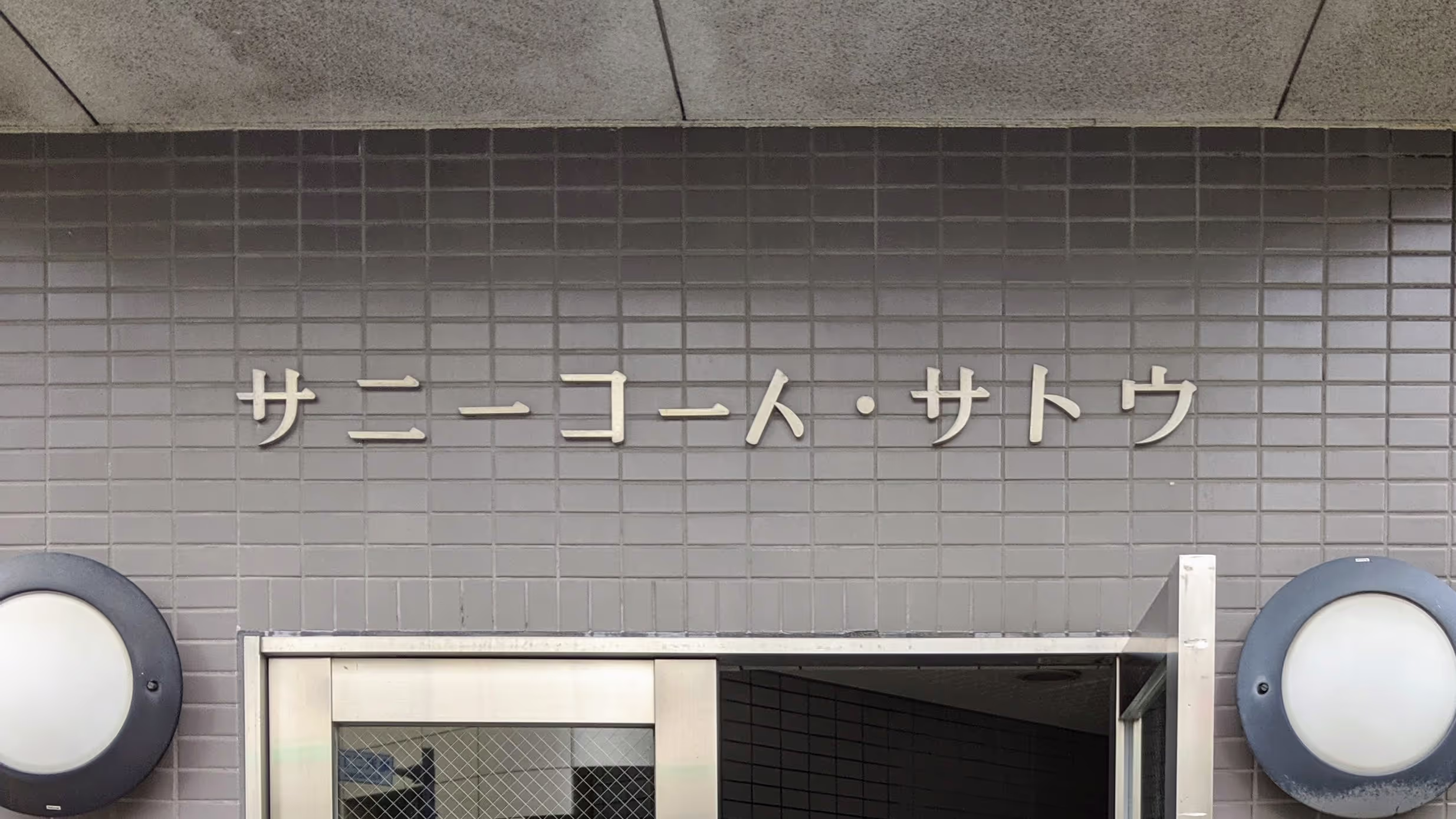 1文字目の「ト」が時計回りに30度ほど回転した「サニーコート・サトウ」。