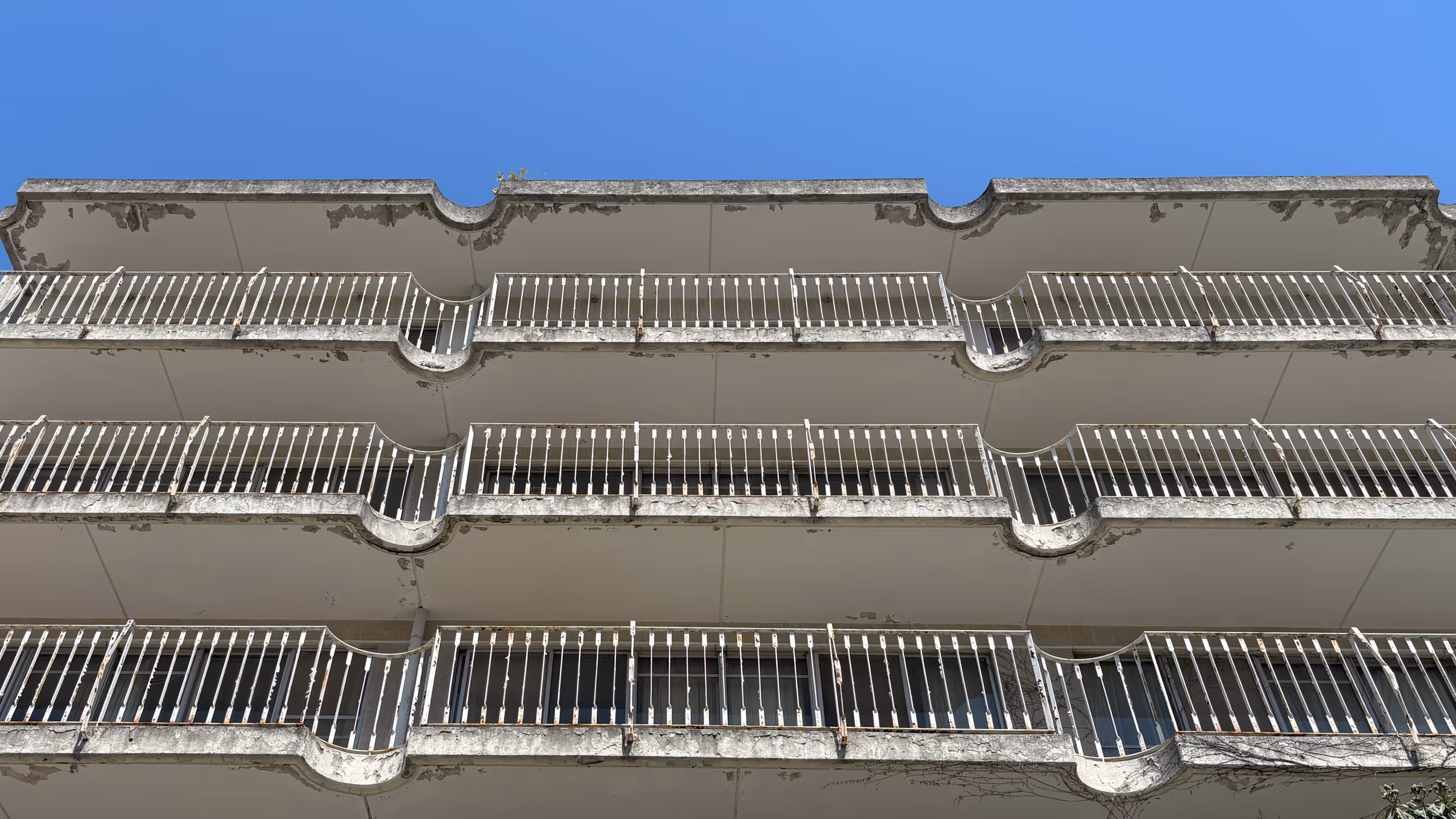 マンションの各階の各ベランダにボロボロの柵が並ぶ。屋根側もかなり剥落があり、放棄されてから長いようだ。部屋同士の間は柵や屋根が半円形に美しく抉られており、往時はなかなか瀟洒な雰囲気であったことが伺える。